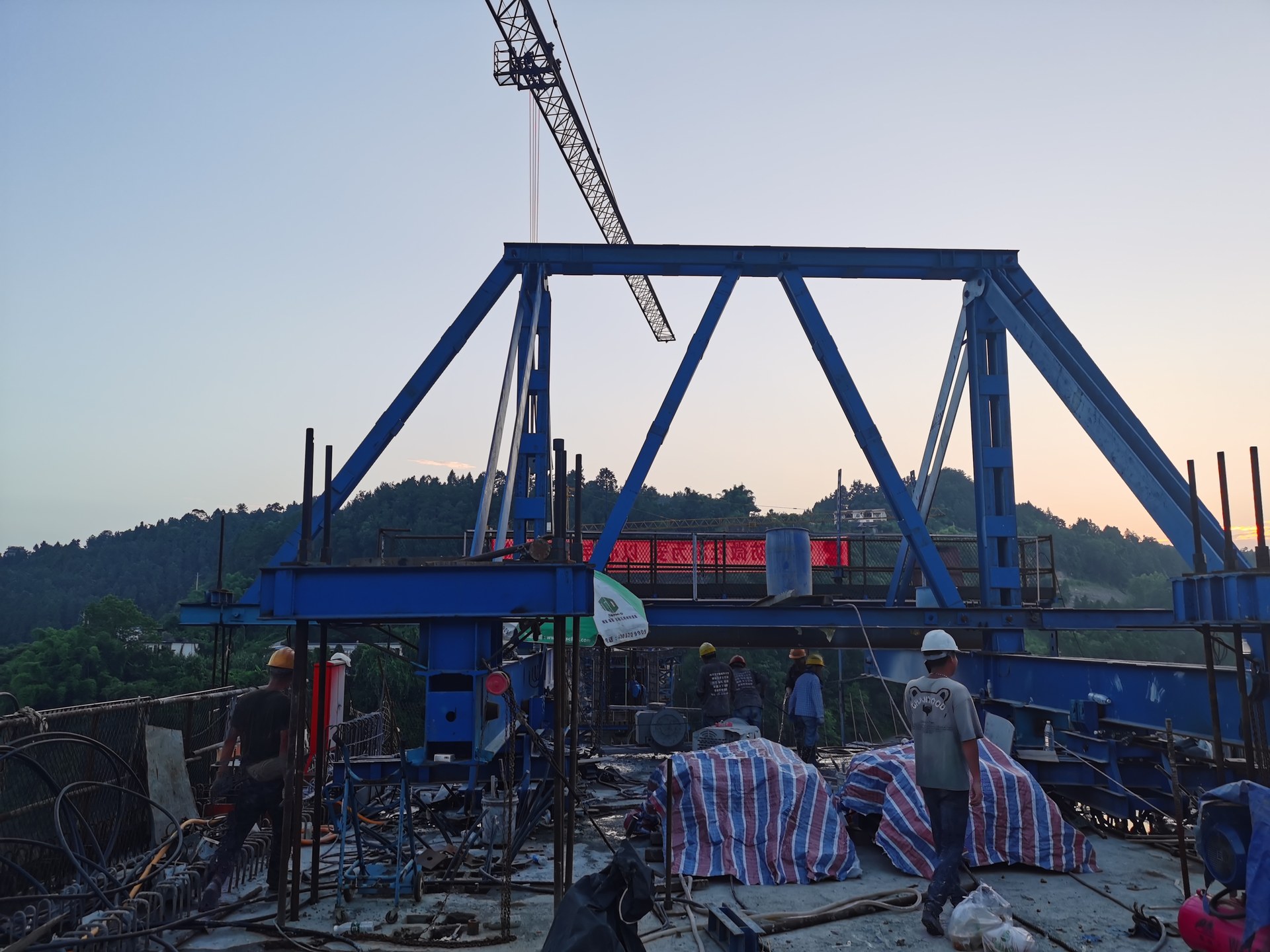 连续梁改造现场：蓝色门架式支架与塔吊协同作业，工人检查切割设备与梁面状况