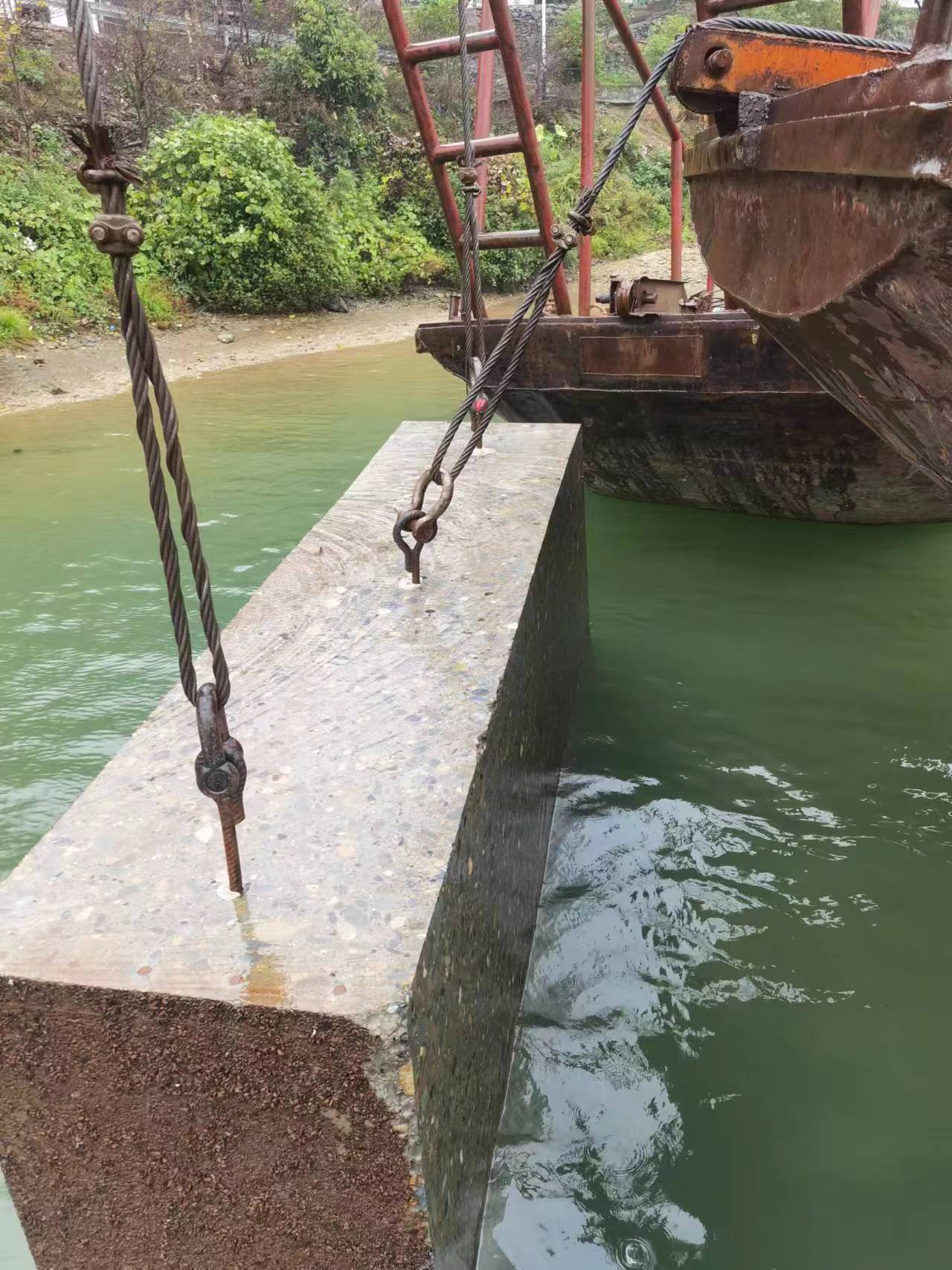 水下切割完成的分块混凝土块用钢丝绳吊索卡环固定，即将从江中吊出